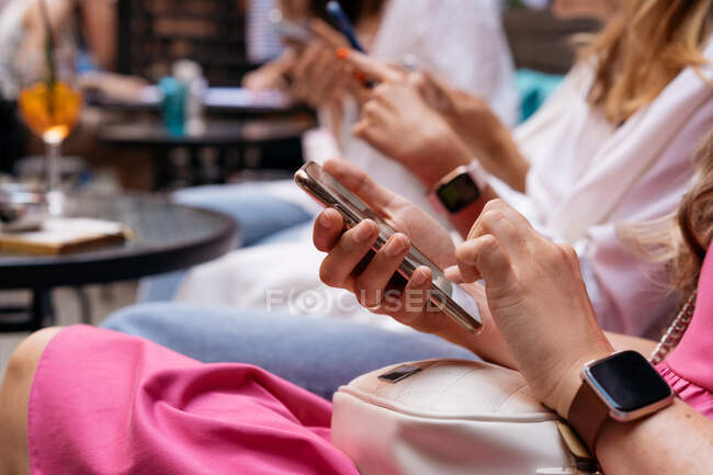 Tiro recortado de pessoas sentadas juntas usando smartphones — Fotografia de Stock