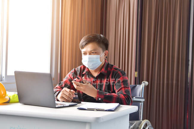 Asian disabled worker in wheelchair using computer — Stock Photo