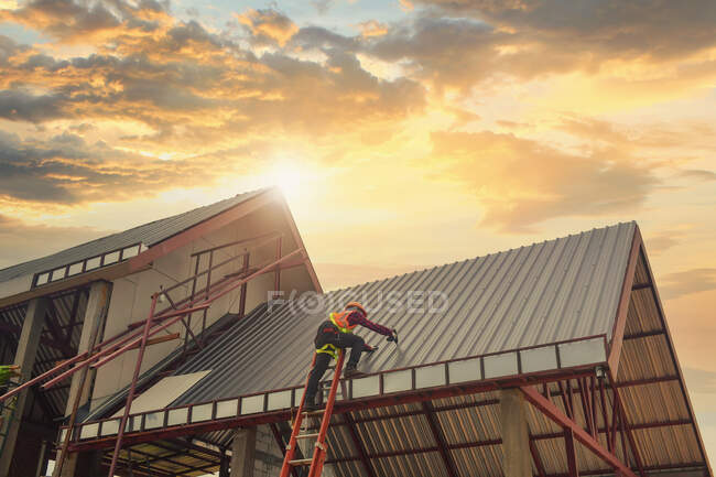 Toiture Travailleur de la construction installer un nouveau toit. Outils de toiture. Perceuse électrique utilisée sur les nouveaux toits avec tôle. — Photo de stock