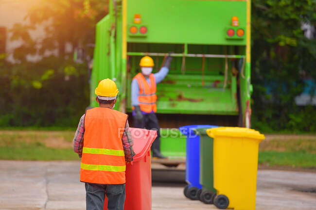 Caminhão de lixo reciclável e o detentor na aldeia.Coletor de lixo no caminhão de lixo. varredor ou trabalhador estão carregando resíduos no transportador de caminhão de lixo. — Fotografia de Stock