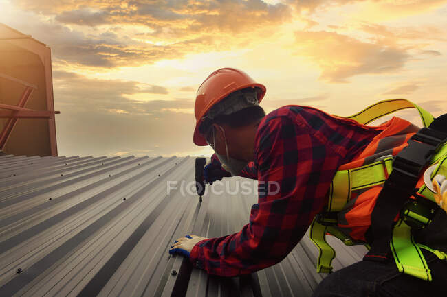 Dachdecker Bauarbeiter montieren neues Dach. Dachdeckerwerkzeuge. Elektrobohrer auf neuen Dächern mit Blech. — Stockfoto
