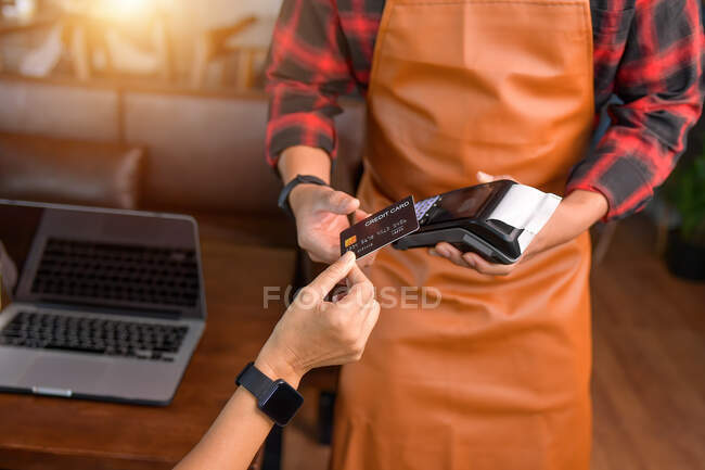 Schnappschuss von Frau, die mit streichender Kreditkarte bezahlt, Kellner, der Terminal hält — Stockfoto