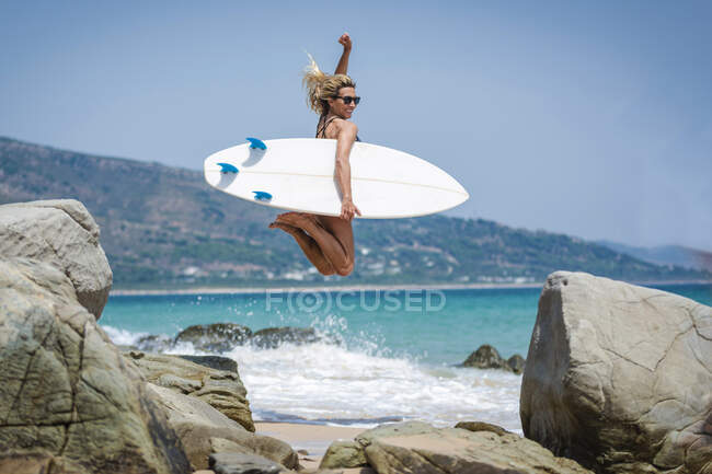 Jeune surfeuse femme à la plage ensoleillée — Photo de stock