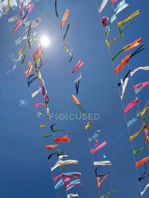 Bandeiras coloridas no céu azul com sol — Fotografia de Stock