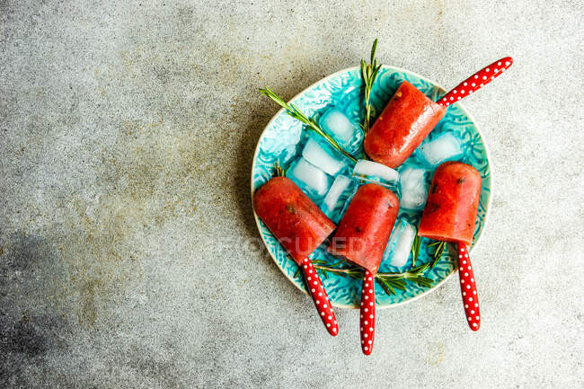 Summer dessert with organic watermelon popsicles served on plate with ice and rosemary — Stock Photo