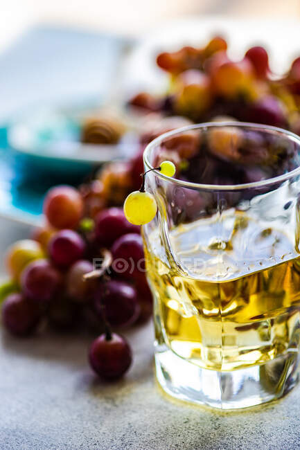 Copo de conhaque chacha georgiano ao lado de um monte de uvas vermelhas na mesa — Fotografia de Stock