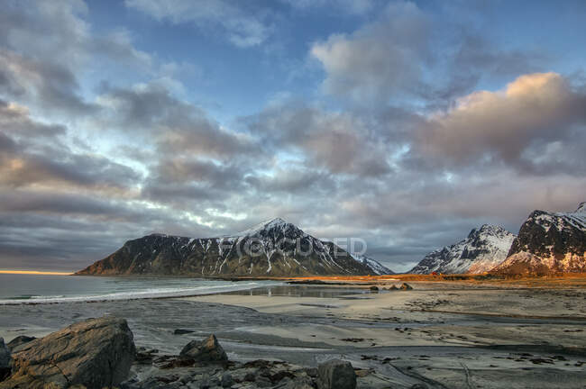 Сцена на скалистом пляже с горами, Стор Санднес, Флакстад, Лоффелланд, Норвегия — стоковое фото