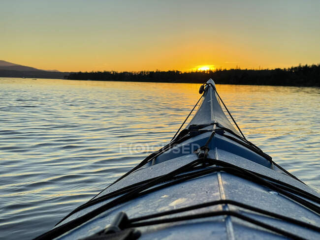Pontos de vista de caiaque navegando na água em direção à costa ao pôr do sol, Canadá — Fotografia de Stock