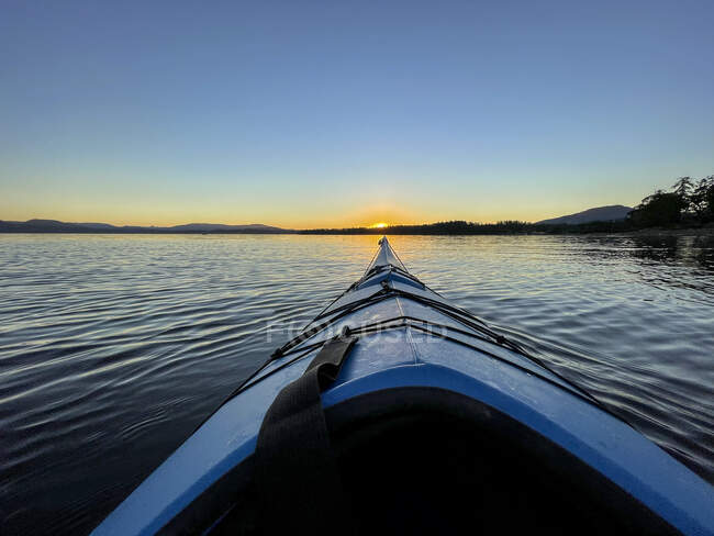Pov de kayak navegando en el agua hacia la costa al atardecer, Canadá - foto de stock