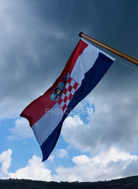 Bandera croata soplando en el viento en el cielo nublado, Croacia - foto de stock