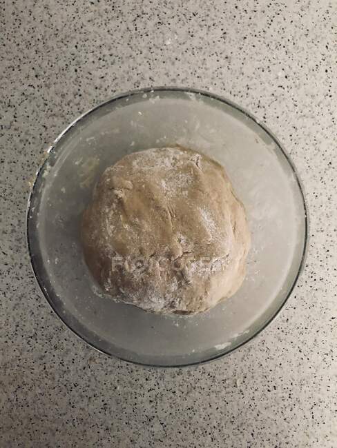 Top view of ball of dough proofing in glass bowl — Stock Photo