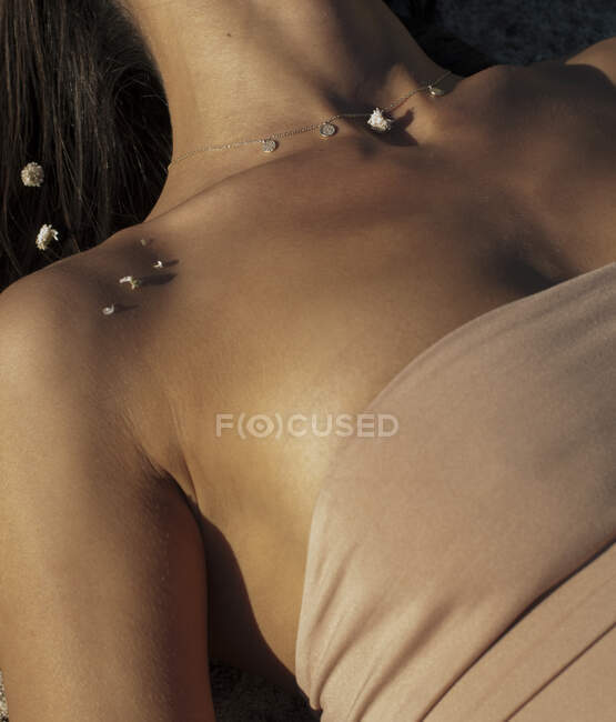 Обрезанный снимок женской груди с цепью и маленькими цветами — стоковое фото