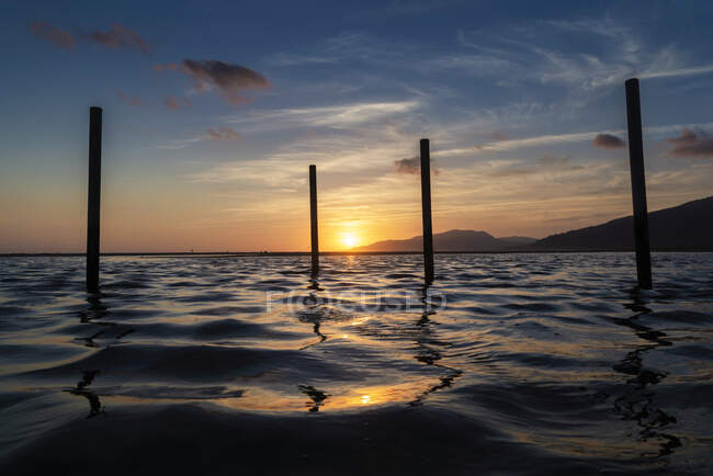 Silhouette di pali di legno in acqua al tramonto, spiaggia di Los Lances, Tarifa, Cadice, Andalusia, Spagna — Foto stock