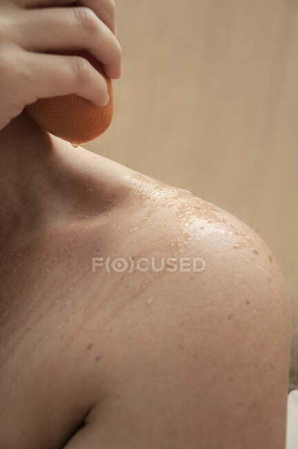 Gros plan d'une femme hydratant sa peau avec une orange fraîche — Photo de stock