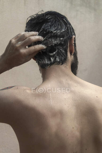 Vista posteriore di un uomo in piedi sotto la doccia lavarsi i capelli — Foto stock