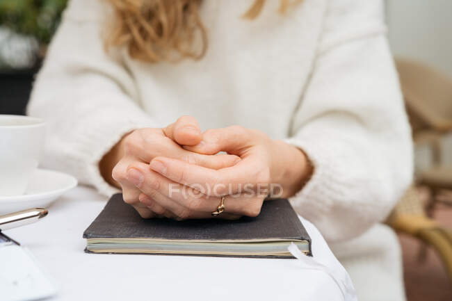 Close up shot of female clasped hands on notebook — Stock Photo