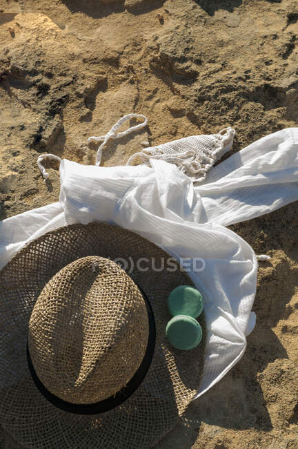 Vestido de verano, sombrero de paja y dos barras de champú en la superficie de la playa de arena - foto de stock