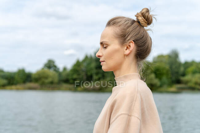 Portrait of beautiful woman meditating outdoors by a river, Belarus — Stock Photo
