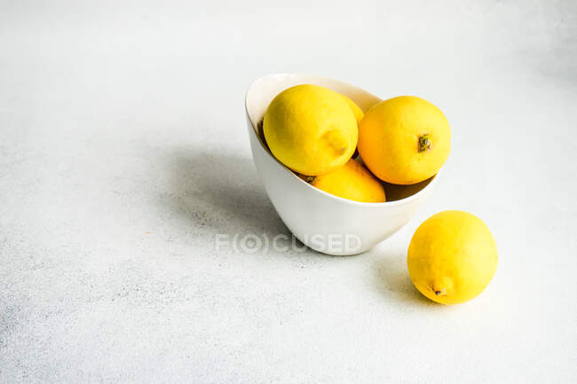 Bowl of fresh lemons on concrete table — Stock Photo