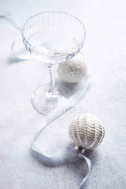 Empty glass with ribbon and christmas baubles — Stock Photo