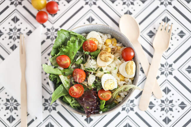 Vue du dessus d'un bol de salade avec maïs doux, tomate, riz, coriandre et oeuf de caille — Photo de stock