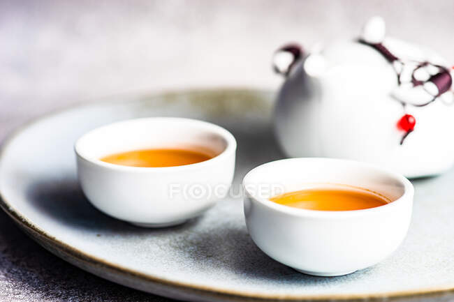 Dos tazas de té y tetera en el plato - foto de stock