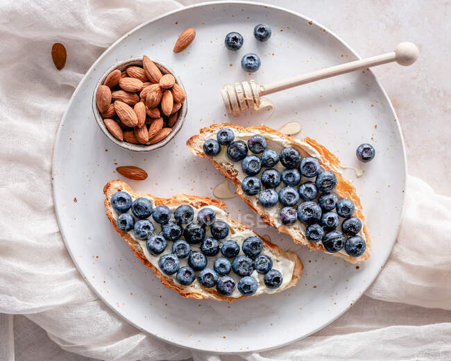 Croissant with cream cheese, fresh blueberries and honey drizzle plus fresh almonds — Stock Photo