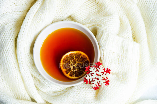 Top view of a cup of tea with a slice of lemon, a knitted sweater and snowflake decoration — Stock Photo