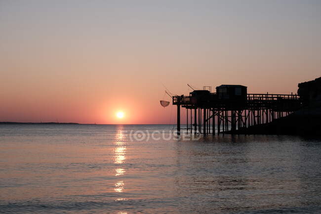 Silhouette of pier with fishermens huts by sea, Meschers-sur-Gironde, Chartente-Maritime, France — Stock Photo