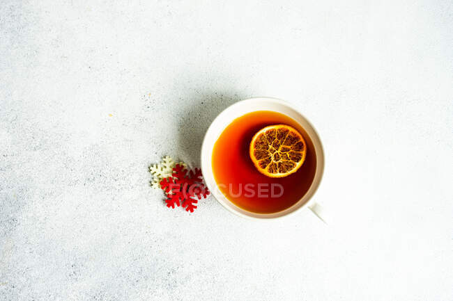 Cup of tea with dried orange slice and snowflakes decorations on table — Stock Photo