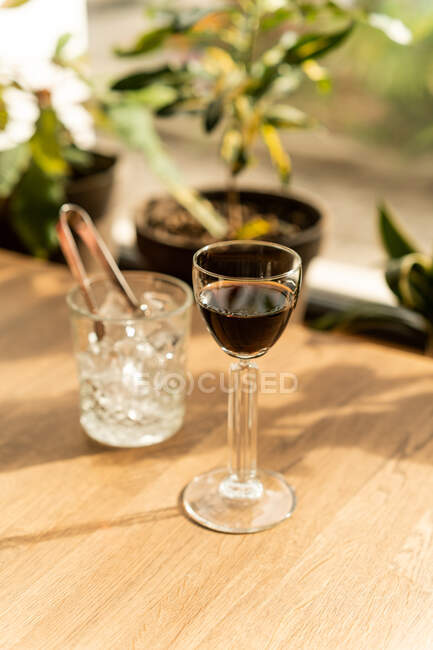 Primer plano de mini copa de jerez sobre mesa con vaso de cubitos de hielo - foto de stock