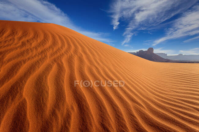 Blick auf gewellte Sanddüne mit weit entfernten Felsen — Stockfoto
