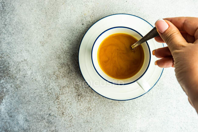 Vista dall'alto di mano femminile che mescola caffè con latte — Foto stock