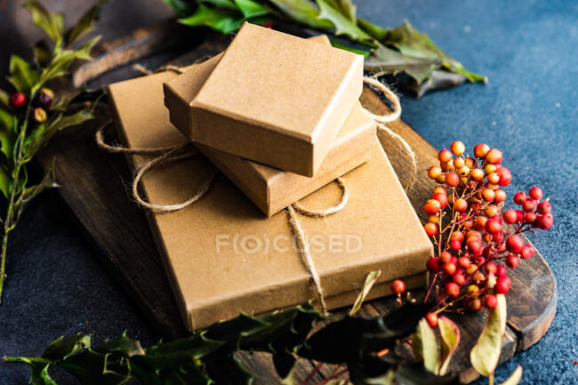 Cajas de regalos pila con ramas de navidad de hojas y bayas rojas - foto de stock