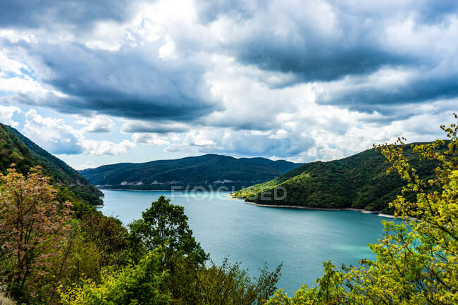 Green mountainous landscape with lake and cloudy sky — Stock Photo