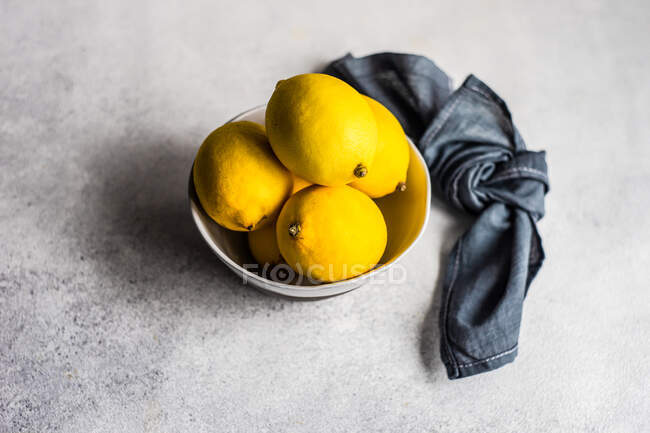 Bowl of lemons and black cloth napkin — Stock Photo
