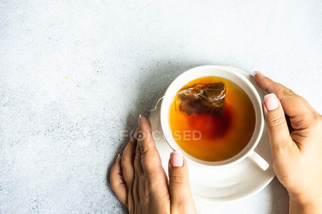 Vista dall'alto di mani femminili con tazza di tè — Foto stock