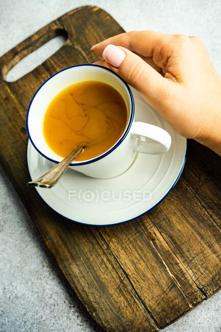 Mano femenina con taza de té de cúrcuma - foto de stock