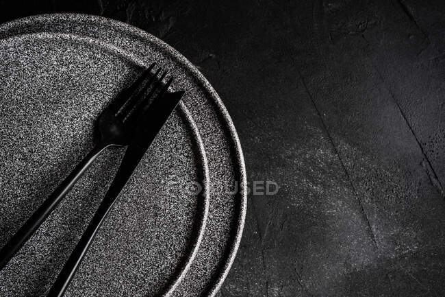 Knife and fork on two plates on dark surface — Stock Photo