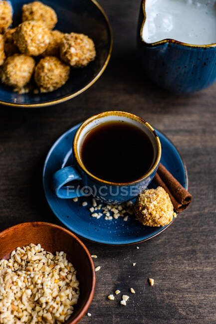 Xícara de café com bolas de doces caseiras saudáveis revestidas em nozes picadas — Fotografia de Stock