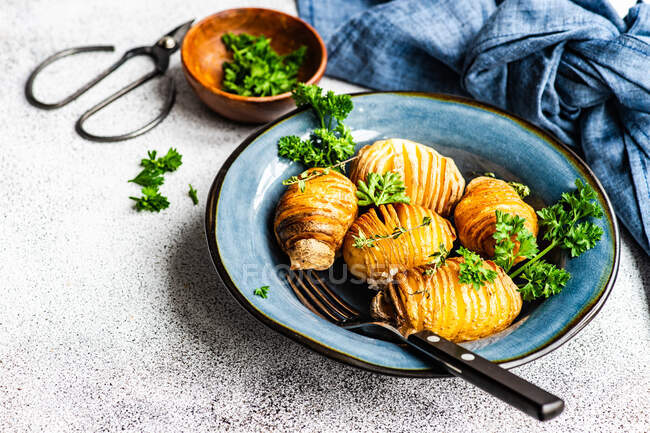 Bowl of hasselback potatoes with fresh parsley and fork — Stock Photo