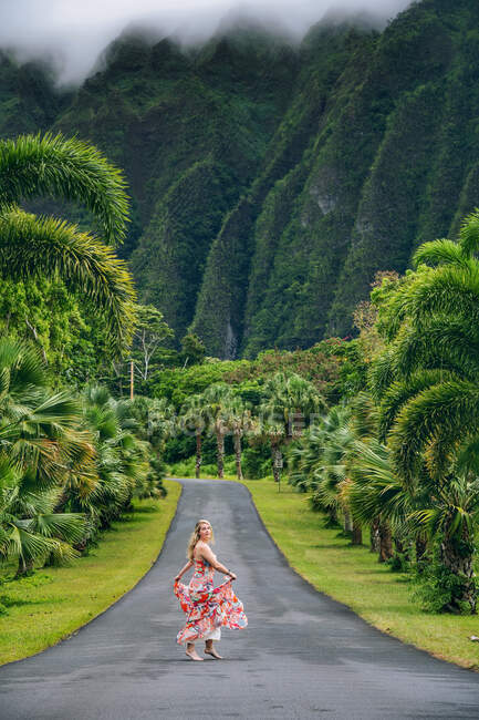 Hermosa mujer girando en medio de una carretera, Oahu, Hawaii, EE.UU. - foto de stock