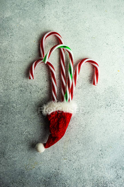 Three red and white candy canes and red, white and green candy cane in santa hat — Stock Photo