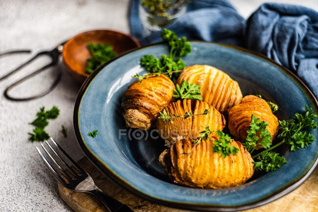 Bowl of hasselback potatoes with fresh parsley served on table — Stock Photo