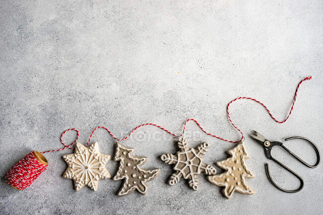 Делать рождественские пряничные украшения из печенья с веревками и ножницами — стоковое фото
