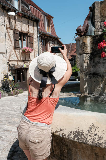 Veduta posteriore di una donna che fotografa una fontana, Carennac, Quercy, Lot, Occitanie, Francia — Foto stock