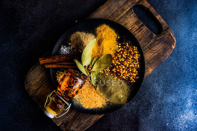 Overhead view of assorted spices in plate on wooden board — Stock Photo
