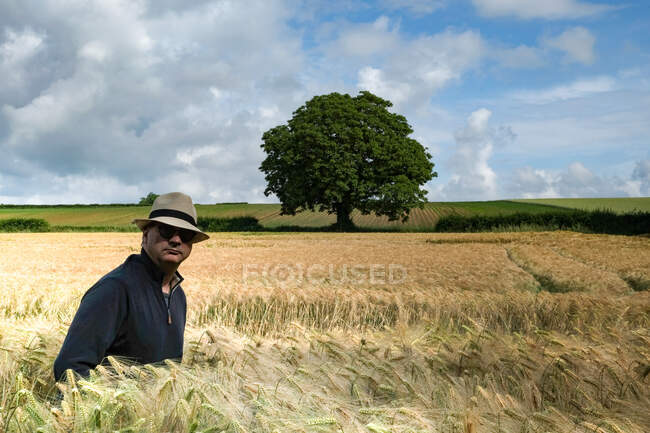 Man in a straw hat walking through a wheat field in summer, France — Stock Photo
