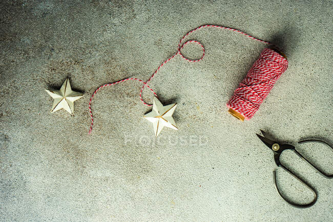 Decoraciones de estrellas, cordeles y tijeras en la mesa para hacer decoraciones navideñas - foto de stock