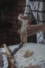 Menschenhände schneiden Teig auf langen Stücken — Stockfoto